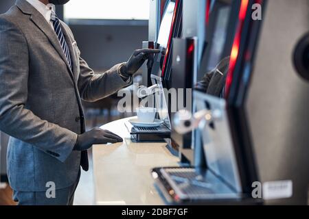 Person in Handschuhen, die eine Kaffeemaschine bedient Stockfoto
