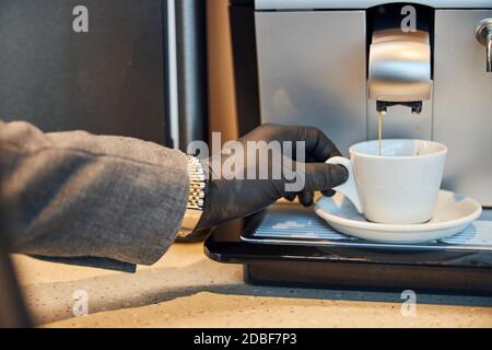 Kaffee aus einer Espressomaschine in eine weiße Tasse gießen Stockfoto