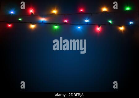 Bunte weihnachtslichter auf dunkelblauem Hintergrund. Farbenfroher Hintergrund für das neue Jahr Design. Frohe weihnachten Grußkarte. Girlanden glühen mit Stockfoto