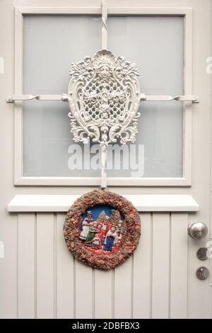 Weihnachtskranz aus Gips mit Weihnachtsszene befestigt Eine weiße Tür eines Hauses irgendwo in den Niederlanden Stockfoto