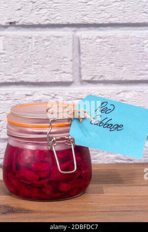 Eingelegter Rotkohl in einem Clip Glas Vorratsglas mit einem Etikett Tag. Auf Holz mit grauem Ziegelhintergrund Stockfoto