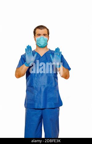 Männlicher Arzt in Peelings mit schützender Gesichtsmaske und Handschuhen, die ein Stoppschild mit Händen und Handflächen zeigen. Einfarbiges weißes Coronavirus-Konzept Stockfoto