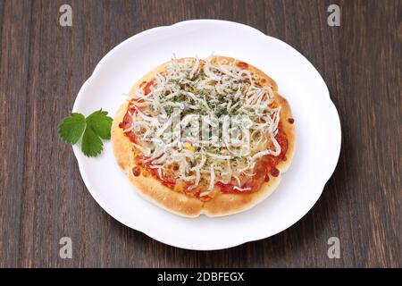 Kleine Fisch shirasu Pizza auf einem Teller mit Holztisch Stockfoto