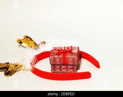 Kleine leuchtende rote Geschenkbox mit Hirsch Golden glitzernden Hörnern auf grauem Hintergrund, kreatives Feiertagskonzept, Neujahrskomposition, Kopierraum Stockfoto