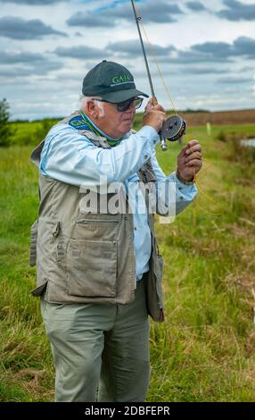 Lincolnshire, Großbritannien - Herr Barry Grantham, ein Ausbilder in Fliegenfischen, wirft eine Fliegenschnur über einen Forellensee für Regenbogenforelle Stockfoto