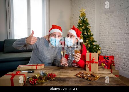 Webcam Ansicht von glücklichen Paar mit Gesichtsmaske auf Videoanruf feiern virtuelle weihnachten und Neujahr Party zu Hause im Lockdown. COVID-19 soziale Distanc Stockfoto