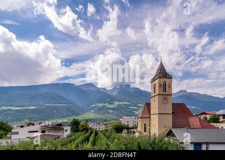 Die Pfarrkirche St. Johannes der Täufer in Corzes, Südtirol, Italien, vor einem dramatischen Himmel Stockfoto