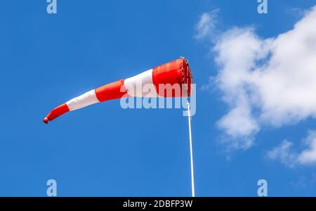 Fliegende Windsack-Windfahne mit roten und weißen Linien gegen Ein blauer Himmel Stockfoto