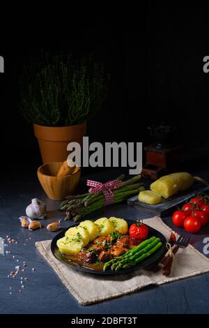 Knödel mit Rindergulasch und grünem Spargel Stockfoto