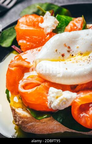 Sandwich mit Lachs, Käse, Kräutern und pochiertem Ei. Stockfoto