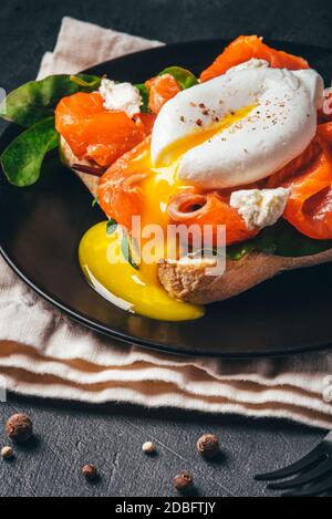 Sandwich mit Lachs, Käse, Kräutern und pochiertem Ei. Stockfoto