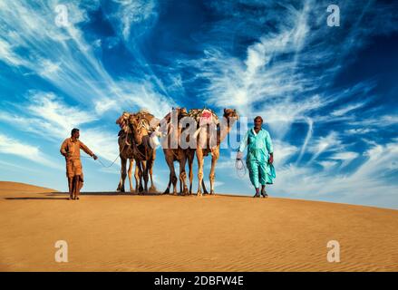 Rajasthan Reise Hintergrund - zwei indische Kamele (Kameltreiber) mit Kamelen in den Dünen der Thar Wüste. Jaisalmer, Rajasthan, Indien Stockfoto