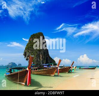 Langes Boot am tropischen Strand mit Kalksteinfelsen, Krabi, Thailand Stockfoto
