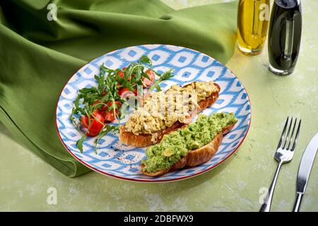 Croissant, Ei, Avocado, Rucola, Kirsche, Trüffel. Frühstücksangebot. Stockfoto