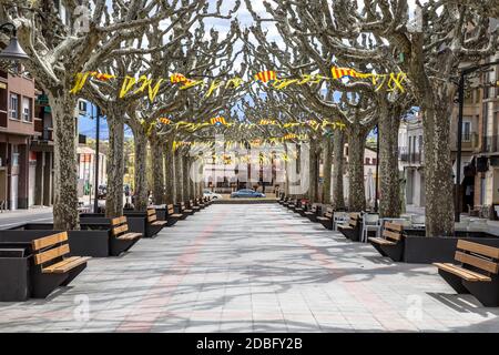 Katalanische Flaggen in der Hauptstraße Rambla mit Schatten von Platanen in der Stadt Tremp in den spanischen Pyrenäen, Katalonien, Spanien, April. Stockfoto