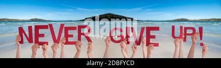 Menschen Hände Halten Bunte Englisch Wort Nie Aufgeben. Meer Und Strand Als Hintergrund Stockfoto