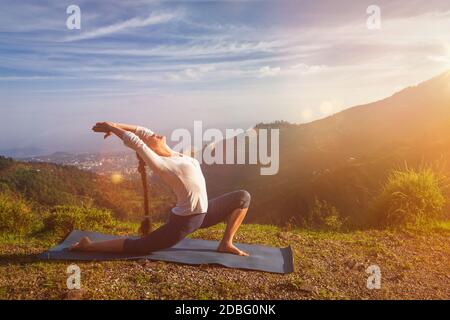 Yoga Outdoor - sportlich fit Frau praktiziert Yoga Anjaneyasana - niedriger Halbmond Ausfallschritt Pose draußen in den Bergen am Morgen. Mit leichtem Leck und Linsenflanell Stockfoto