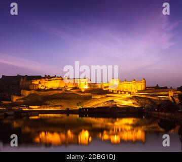 Amer Fort (Amber Fort) beleuchtet in der Nacht - eine der wichtigsten Sehenswürdigkeiten in Jaipur, Rajastan, Indien Refelcting in Maota See in der Dämmerung Stockfoto