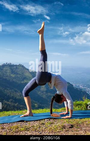Yoga Outdooors - Frau, die Yoga asana eka pada urdva dhanurasana aufwärts Bogen Pose zurück biegen im Freien im Himalaya in Am Morgen Stockfoto