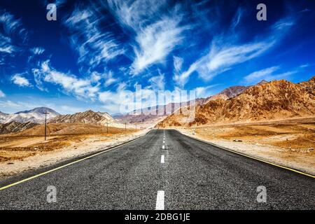 Straße im Himalaya Gebirge und dramatische Wolken am blauen Himmel. Ladakh, Jammu und Kaschmir, Indien Stockfoto