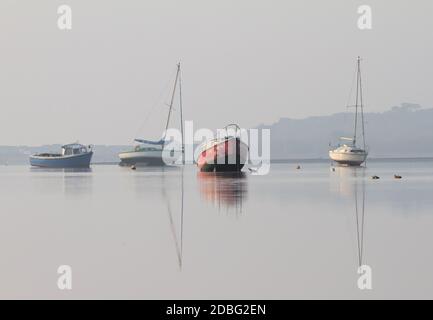 Spiegelung der Boote bei Low Tide an EINEM misty Morgen In Christchurch Harbour Großbritannien Stockfoto