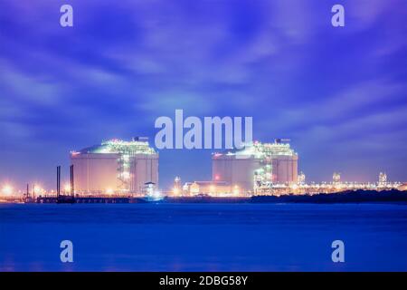 Industriell verflüssigtes Erdgas (LNG) Reservoir Tanks im Seehafen In der Dämmerung Stockfoto