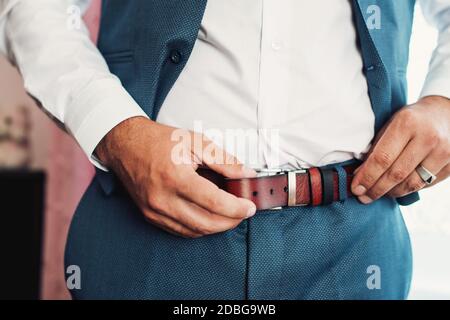 Geschäftsmann, der einen Gürtel, Mode und Kleidung Konzept, Bräutigam immer bereit am Morgen vor der Zeremonie Stockfoto