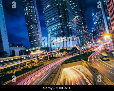 Straßenverkehr in der Nacht. Bürohochhäuser und viel Verkehr auf der Autobahn Straße mit verschwommenen Autos leichte Wege. Hongkong, China Stockfoto