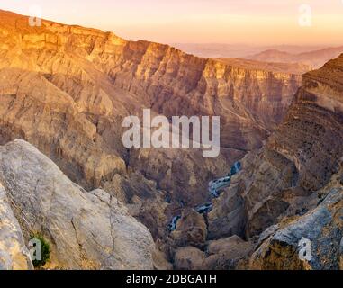 Panoramablick von Wadi Ghul aka Grand Canyon von Arabien in Jebel Shams, Oman bei Sonnenuntergang Stockfoto