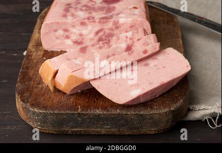 In Scheiben geschnittene gekochte Wurst mit Scheiben von ganz Fleisch auf einem braunen Holzbrett, Nahaufnahme Stockfoto