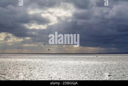 Dramatische beleuchtete Küstenlandschaft, darunter einige Kitesurfer bei Neuharlingersiel in Ostfriesland Stockfoto