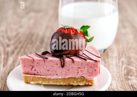 Joghurt Souffle Kuchen mit Erdbeeren in Schokolade auf einem dekoriert Untertasse mit einem Glas Milch Stockfoto