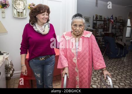Porträt einer einhundert Jahre alten Frau mit ihrem Sozialarbeiter, der sie regelmäßig zu Hause in East Harlem, New York City, überprüft. Stockfoto