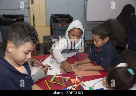 Eine Gruppe von Kindern im Grundschulalter machen Kunstwerke in einem Gemeinschaftszentrum nach der Schule auf der Lower East Side, Manhattan, New York City. Stockfoto