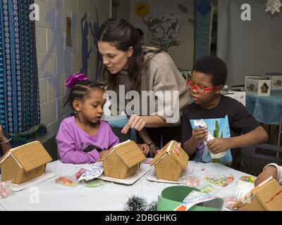 Unterprivilegierte Kinder bauen und dekorieren Lebkuchenhäuser auf einer Weihnachtsfeier in einem Gemeindezentrum in Manhattan, New York City. Stockfoto