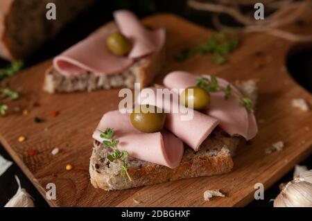 Sandwich mit Wurst und Oliven auf einem Holzbrett Stockfoto