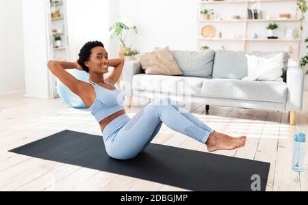 In voller Länge Porträt der jungen schwarzen Frau Ausübung auf Sportmatte, Training ihre Kernmuskeln zu Hause Stockfoto