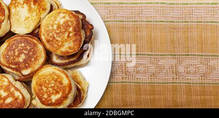 CHISINAU, MOLDAWIEN - 18. Mai 2020: Stapel frisch gebackener Pfannkuchen lagen auf einem weißen Teller auf einem Folk-Stickstoff, der aus nächster Nähe handgefertigt wurde. Draufsicht Stockfoto