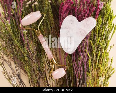 Quartz guasha Gesicht Roller auf floralem Hintergrund Stockfoto