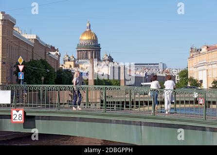 Sankt Petersburg, Russland – 13. Juni 2020: Menschen auf der Krasnoflotski Brücke über den Fluss Mojka. Im Hintergrund ist die Isaakskathedrale Stockfoto