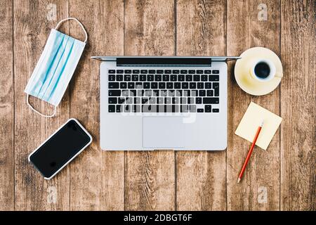 Büro-Arbeitsplatz und Home Office-Schreibtisch während COVID Pandemie. Laptop-Computer mit Gesichtsmask. Stockfoto