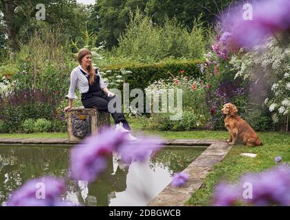 Innenarchitektin Flora Soames und ihr Hund Humbug, fotografiert in ihrem Wiltshire Zuhause. Flora trägt Latzhose der Carrier Company, darunter nichts Stockfoto