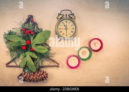 Weihnachtsdekoration auf dem Tisch mit brennenden Kerzen, Weihnachtsbaum, Beeren und Retro-Wecker Stockfoto