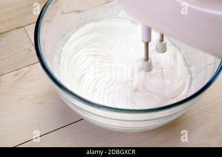 Schlagsahne-Mixer in einer Glasschüssel auf einem Holztisch Stockfoto