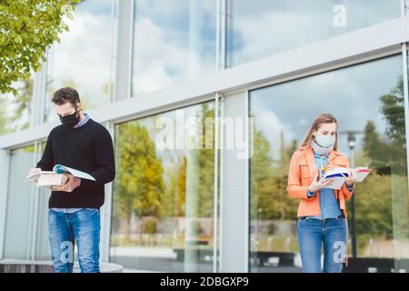 Studenten lernen auf dem Campus halten soziale Distanz, im Hintergrund das Hauptgebäude Stockfoto