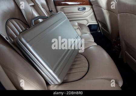 Luxus Metall Aktenkoffer auf dem Auto-Rücksitz. Creme Leder Stockfoto