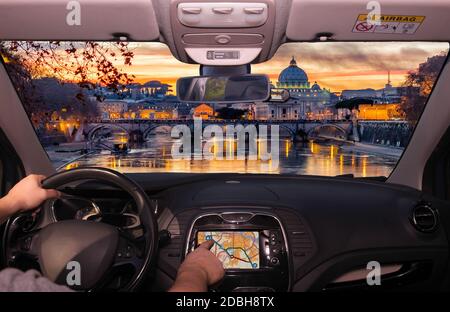 Fahren Sie mit dem Auto während Sie den Touchscreen eines GPS-Navigationssystems in Richtung St. Peter Kirche bei einem wunderbaren Sonnenuntergang in Rom, Italien Stockfoto