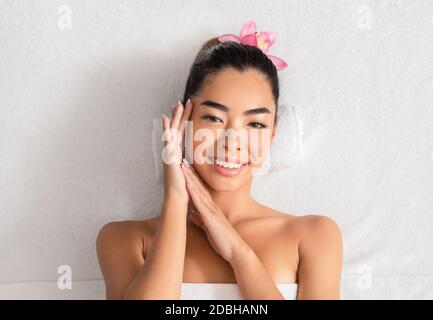 Wunderschöne asiatische Frau, die auf dem Massageliegen im Spa Salon liegt, von oben gesehen Stockfoto