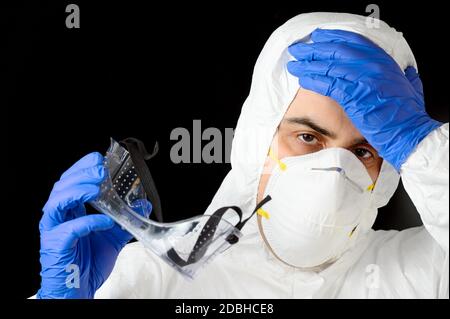 COVID-19. Erschöpfter Arzt, in persönlicher Schutzausrüstung, besorgt, wie die Coronavirus-infizierte Fälle und Todesgebühren steigt. Emotionaler Stress der Hea Stockfoto