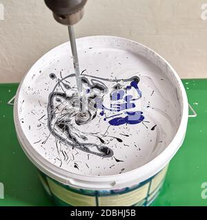 Handwerker macht neue Farbe in den Korb mit Hilfe von Mischer während der Renovierung, um Wand zu malen. Home Maler mischt Farben mit Bohrer. Stockfoto